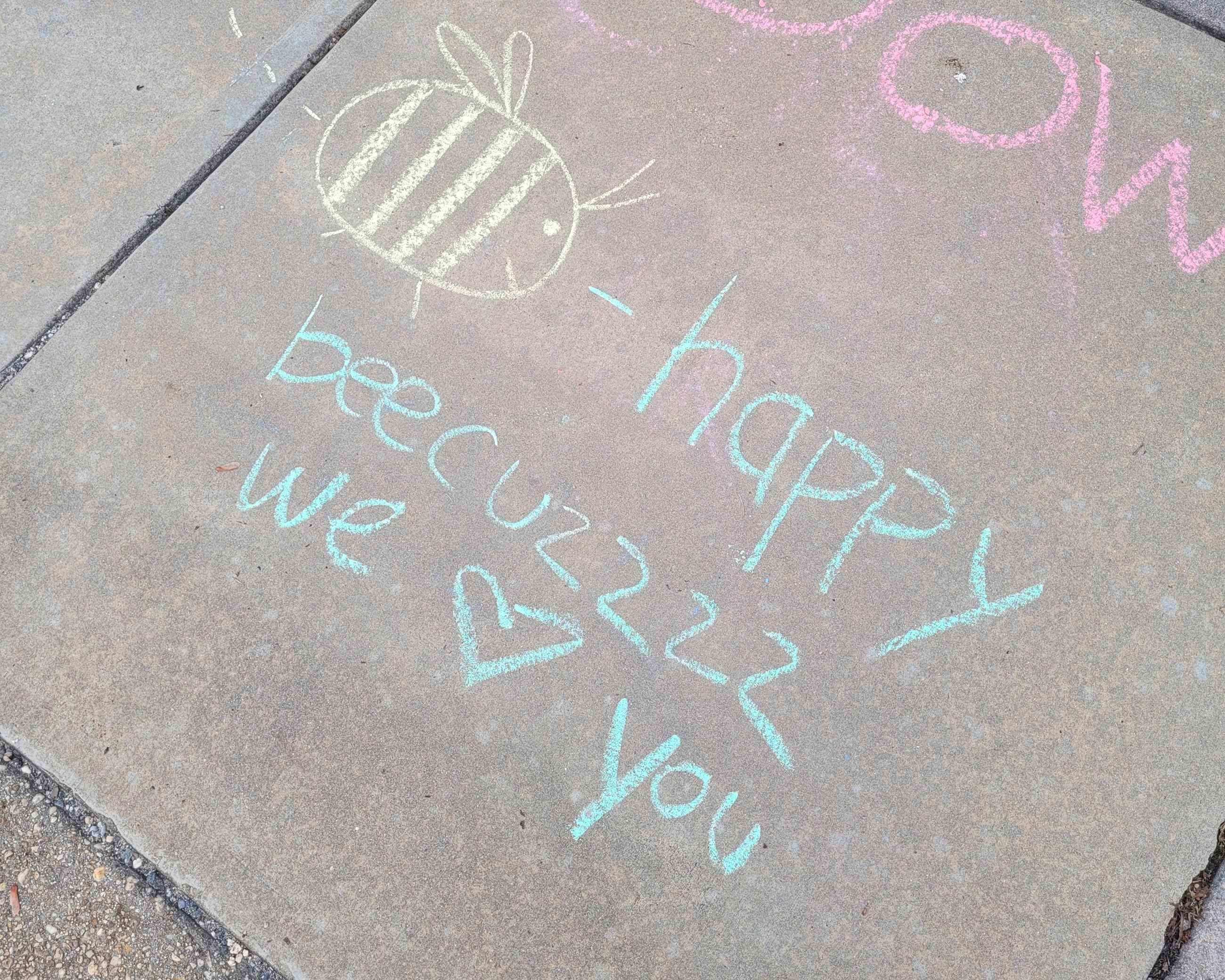 Sidewalk chalk art of a bee with text "bee happy beecuzzzz we heart you."