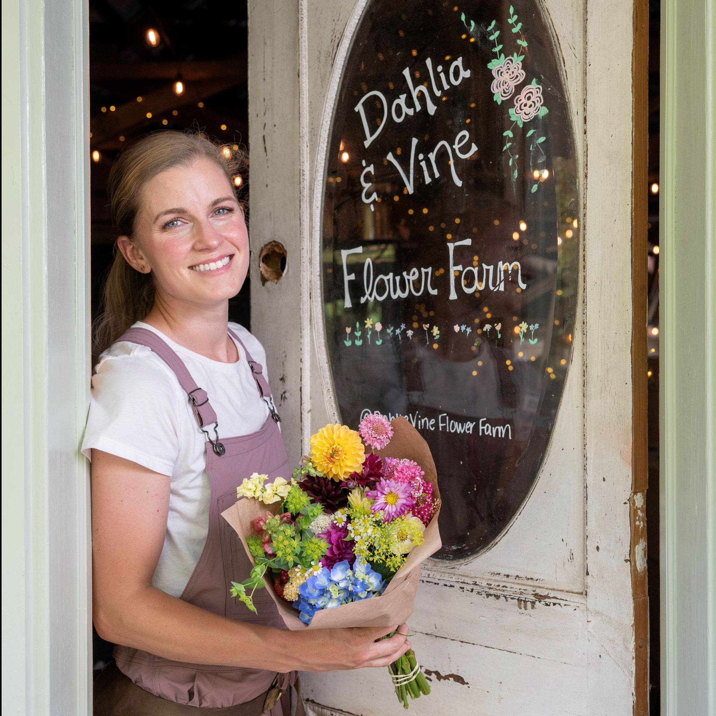 woman holding bouquet of flowers in front of a wooden door
